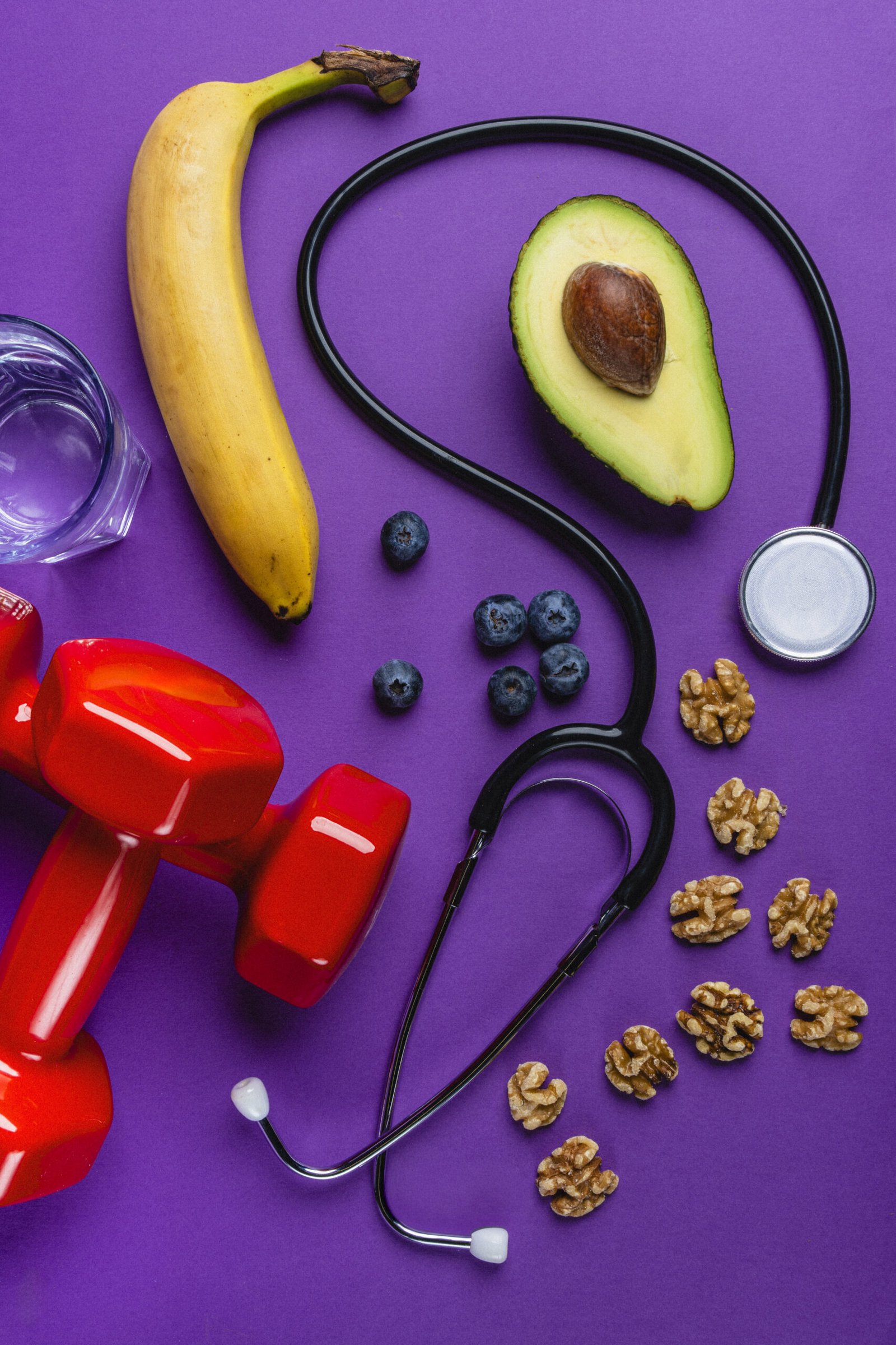 Healthy lifestyle flat lay with potassium food and dumbbells on purple background